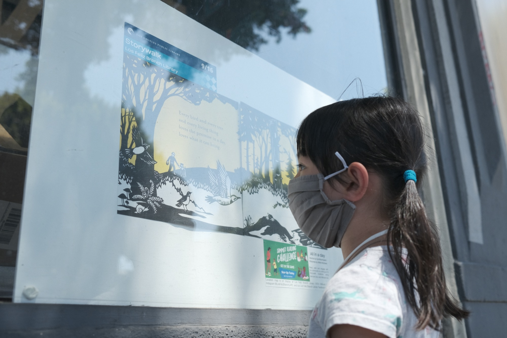 Child reading a Storywalk book panel displayed at the Skylight Books window in Los Feliz.